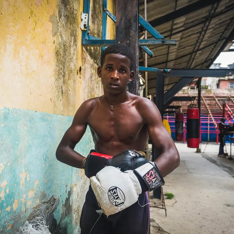 A young boxer in gloves standing outside an open-air gym
