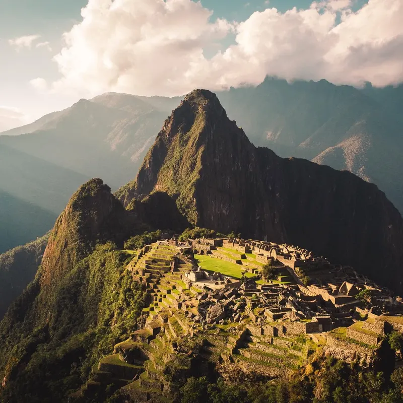 The terraces of Machu Picchu with the peaks around them lit by afternoon sun